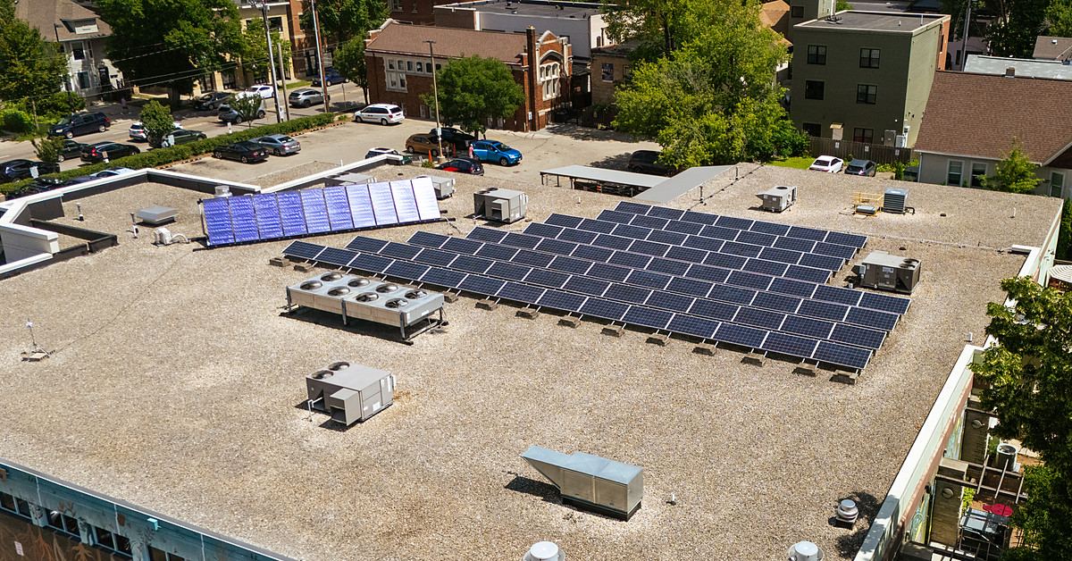 Commercial flat-roof solar array with a downtown skyline behind it