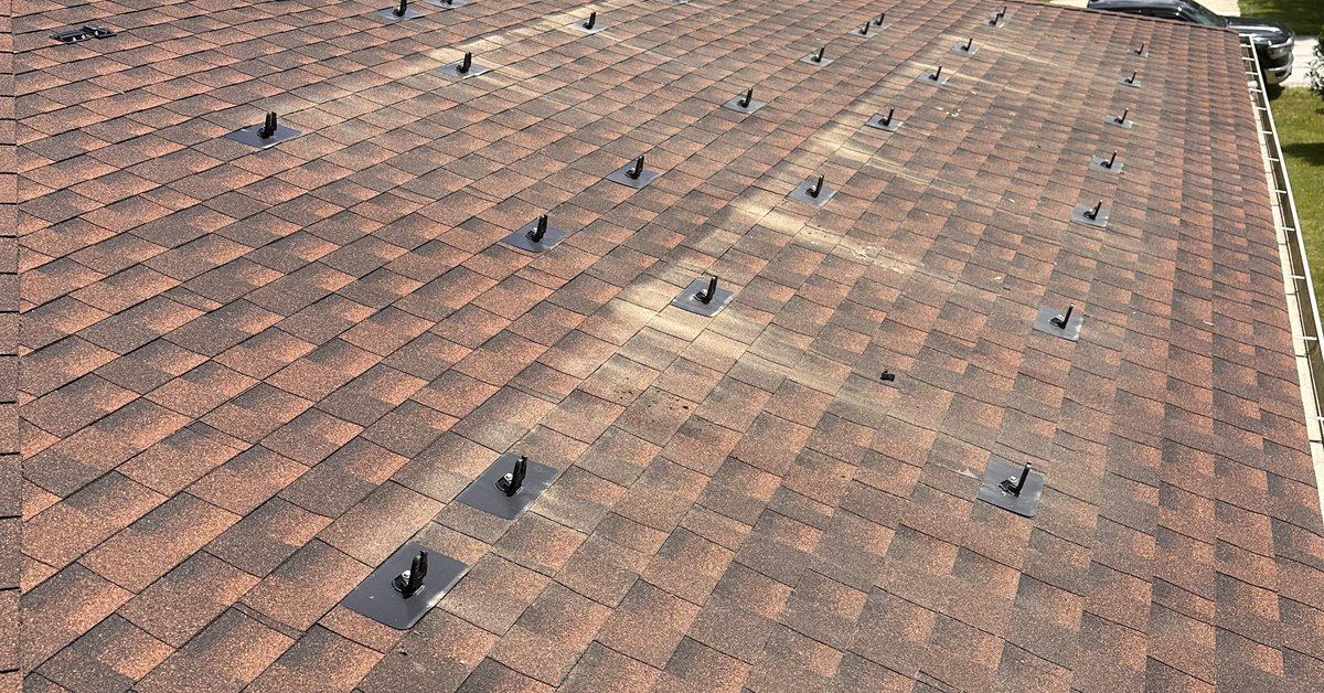 A shingle roof with the solar array removed, mounting feet and flashings still in place