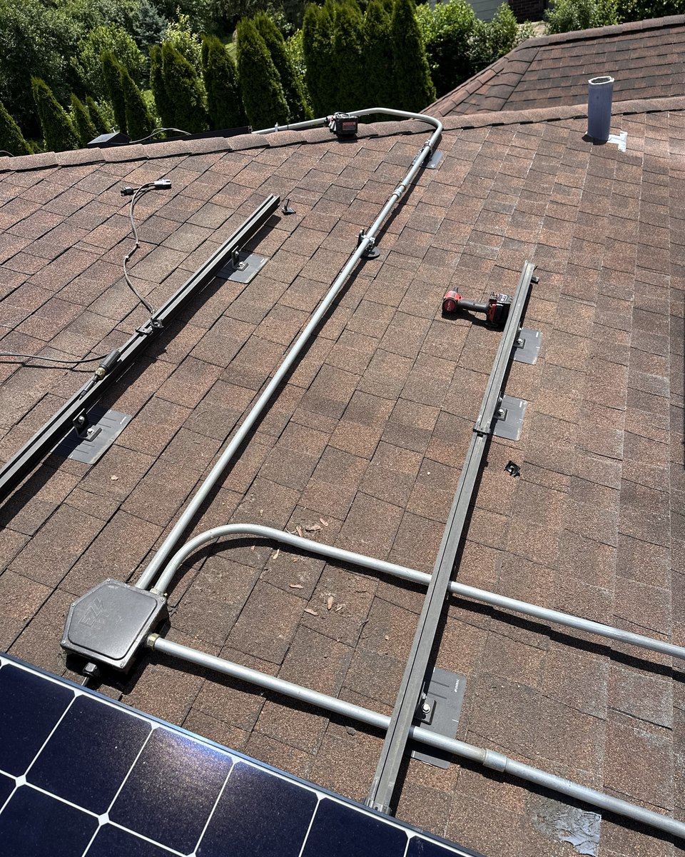 Rails and conduit set on a roof mid-way through a solar reinstall