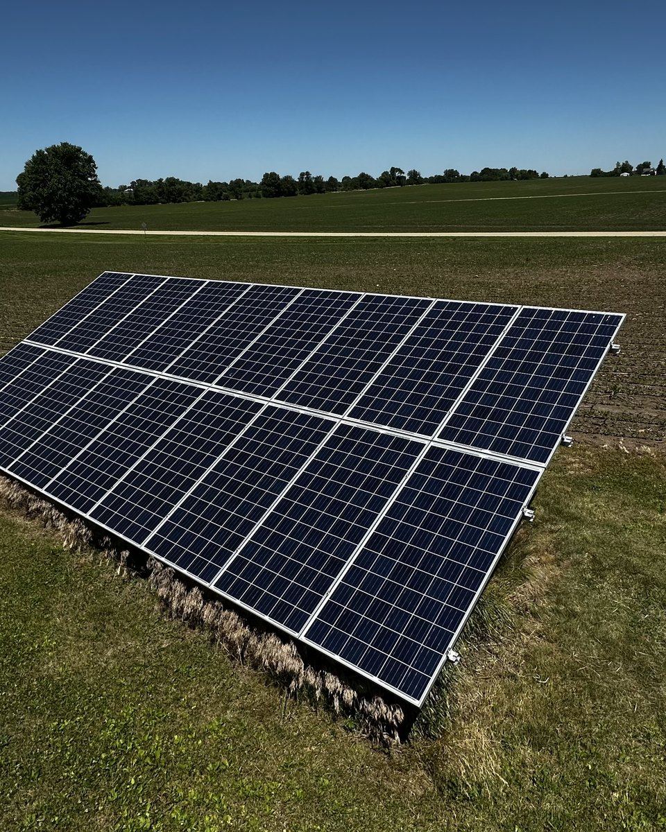 Elevated view of a ground-mounted solar array in a worked farm field