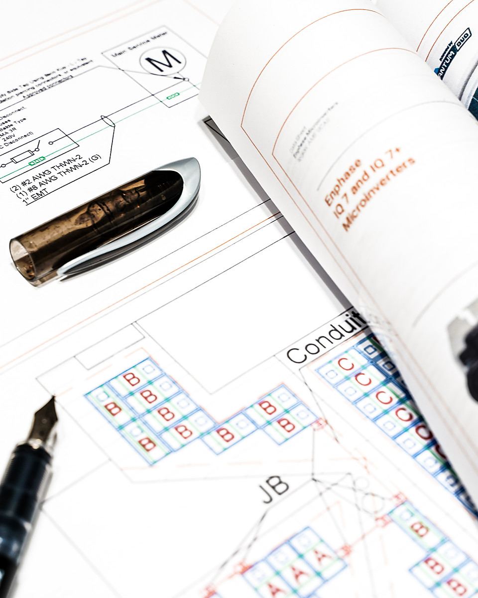 Printed solar system plans and equipment specifications laid out on a table