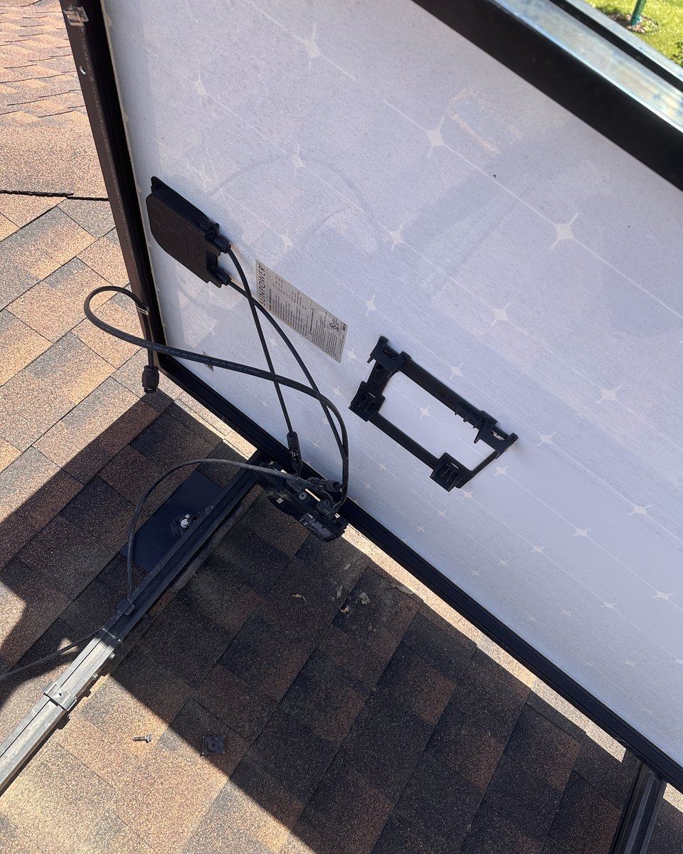 A solar module lifted off its rail, showing the backsheet and module-level electronics